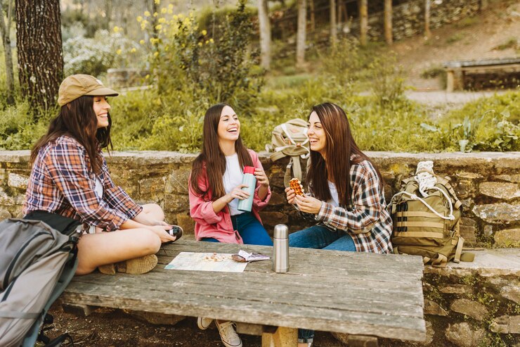 groupe de femmes assises à une table en pleine nature, rigolant avec une boisson à la mains